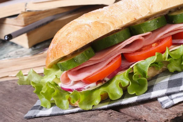 Ciabatta with ham and vegetables on a background of books — Stock Photo, Image