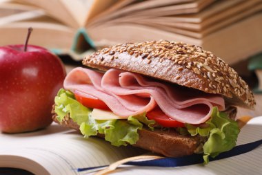 jambon ve sebze ve açık defter üzerinde kırmızı elma ile sandviç