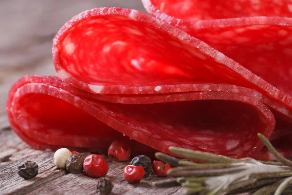 Salami close-up op oude bureau met specerijen en rozemarijn — Stockfoto