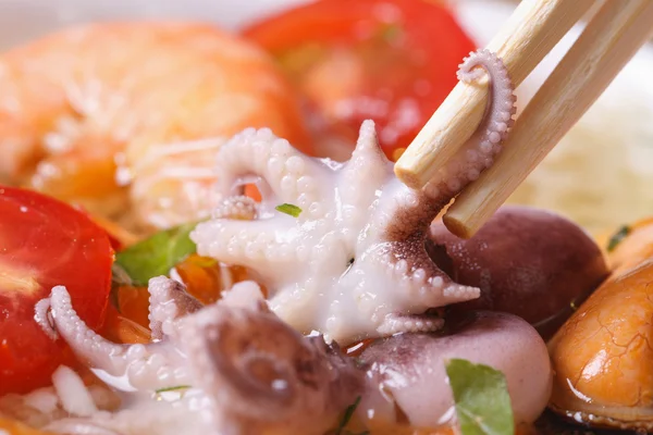 Octopus is clamped by chopsticks against other seafood — Stock Photo, Image