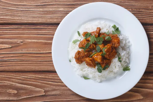 Hühnercurry mit Reis und Koriander auf einem Teller von oben — Stockfoto