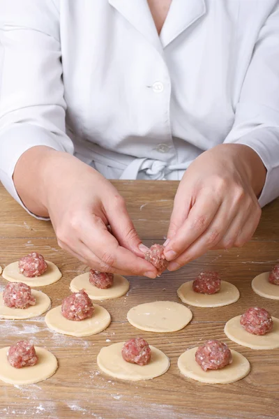 Cook hands closeup on round dough puts meat filling — Stock Photo, Image
