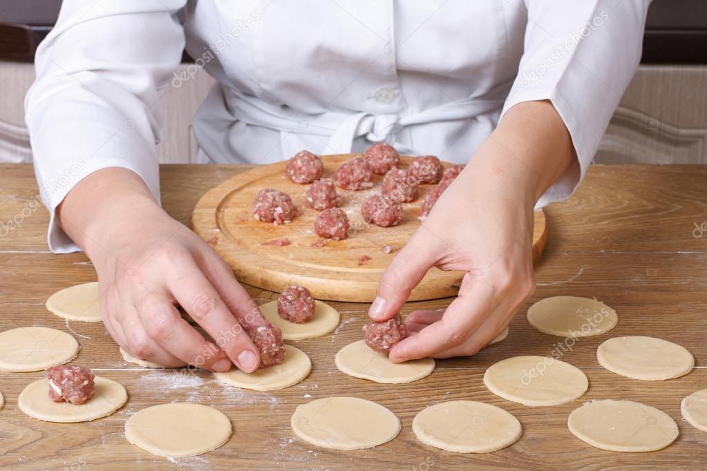 Cook hands lay out minced meat on dumplings