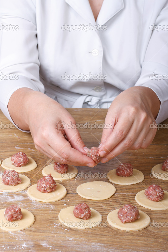 Cook hands closeup on round dough puts meat filling