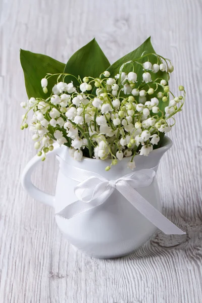 Beautiful bouquet of lilies of the valley in a white jug — Stock Photo, Image