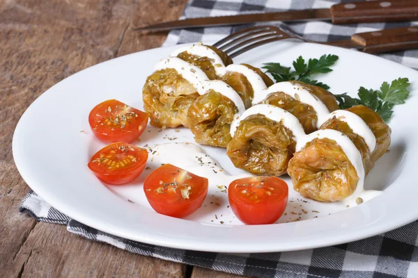 Cabbage rolls with sour cream and tomatoes on a white plate — Stock Photo, Image