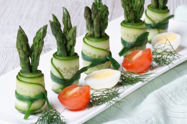 bir plaka üzerinde yeşil kuşkonmaz ile taze salatalık ruloları