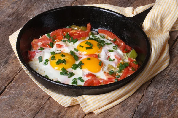 Fried eggs with tomatoes and onions in a pan — Stock Photo, Image