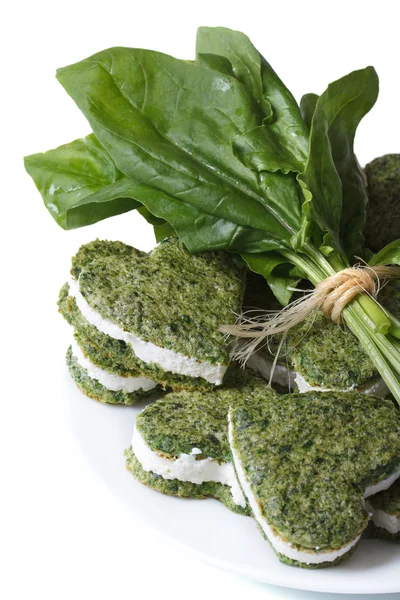 Tasty green heart shaped cookies and fresh spinach — Stock Photo, Image