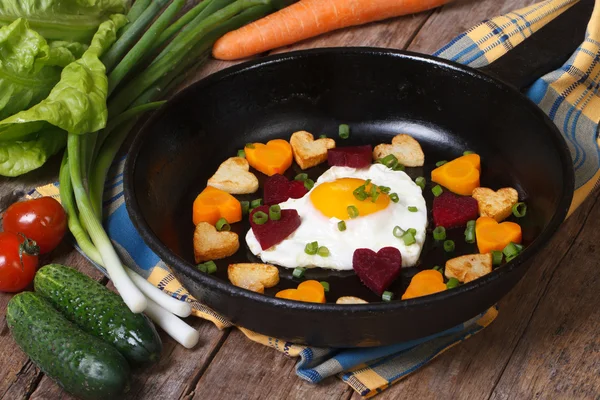 Corações de cenouras, batatas, beterrabas e ovos em uma frigideira — Fotografia de Stock