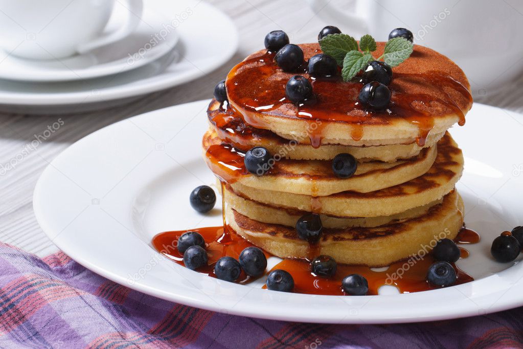 Pancake with blueberries and maple syrup on a white plate