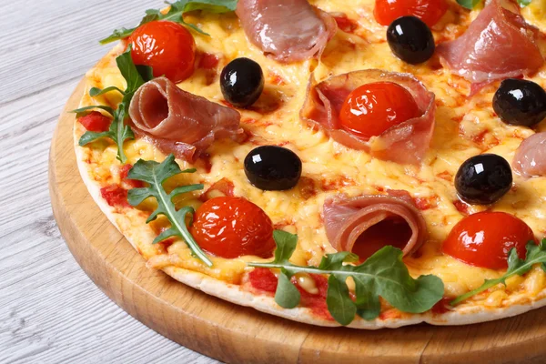 Pizza z prosciutto szynka, pomidory, ser i rukolą zbliżenie — Zdjęcie stockowe