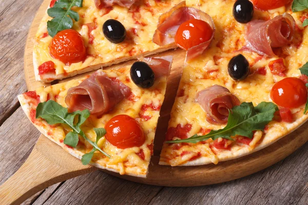 Sliced pizza with  prosciutto, tomatoes and arugula closeup — Stock Photo, Image