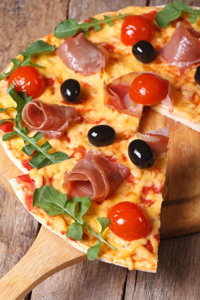 Sliced pizza with ham, tomatoes,  olives and arugula vertical — Stock Photo, Image