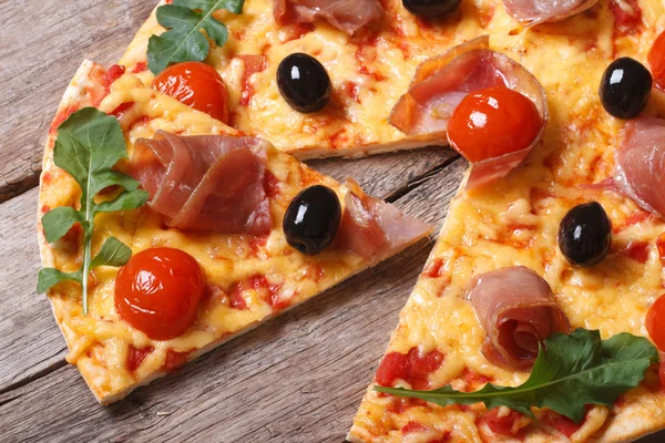 Pieces of pizza with prosciutto, arugula and tomatoes close-up — Stock Photo, Image