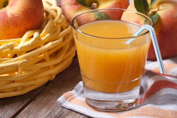 Peach juice in glass closeup on a table and fruit. Horizontal — Stock Photo, Image