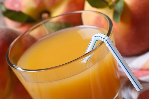 Fresh peach juice in glass macro on a background of ripe fruit — Stock Photo, Image