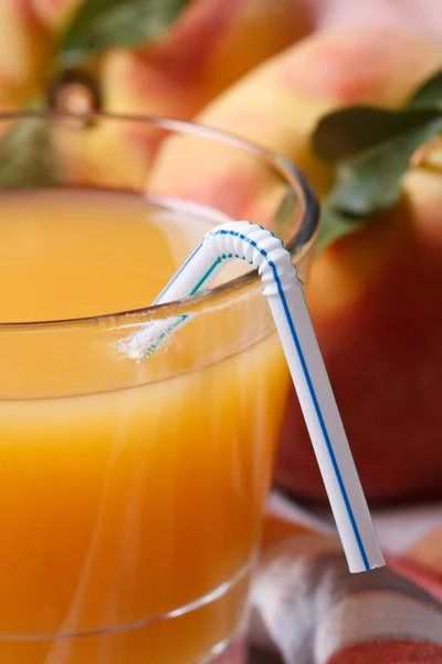 Fresh peach juice in glass macro and ripe fruit. Vertical — Stock Photo, Image