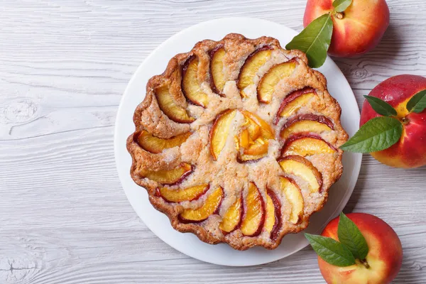 Персиковий пиріг і свіжі фрукти на дерев'яному вид зверху — стокове фото