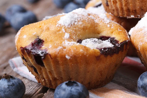 Deliziosi muffin ai mirtilli con zucchero a velo su un tavolo di legno — Foto Stock