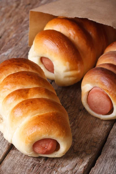 Roll with sausage close up in a paper bag vertical — Stock Photo, Image