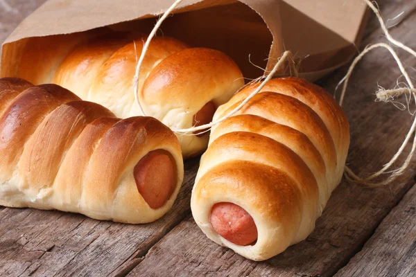 Rolls with sausage closeup unpacked paper horizontal — Stock Photo, Image