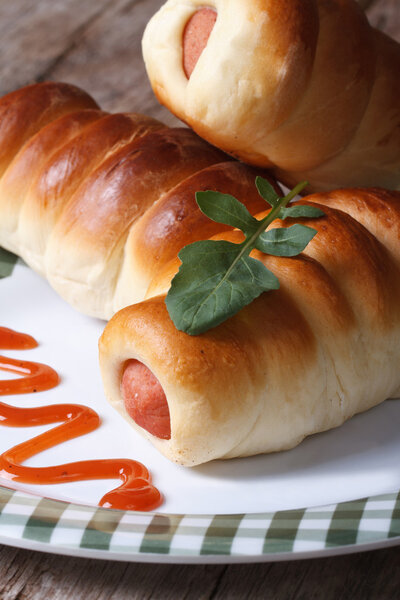 Sausage rolls on a plate with tomato sauce macro vertical