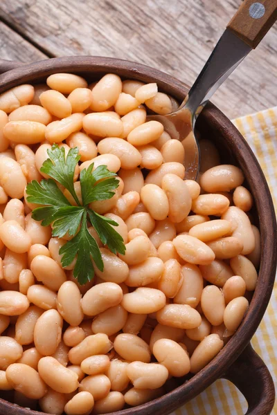 Boiled white beans in a bowl on wooden macro vertical top view — Stock Photo, Image