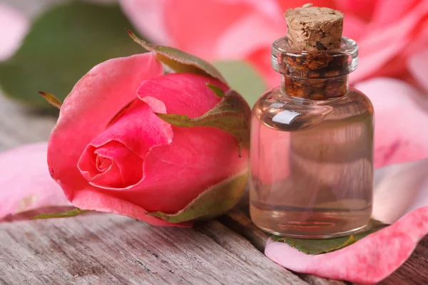 Ulei de trandafir și floare roz frumoasă pe masă de lemn — Fotografie, imagine de stoc