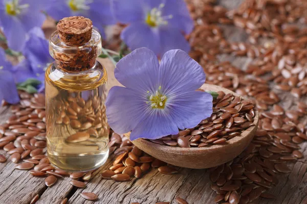 Sementes de linho em uma colher e óleo em uma garrafa close-up horizontal — Fotografia de Stock