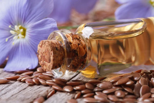 Flores y semillas de lino, aceite en botella de vidrio macro —  Fotos de Stock