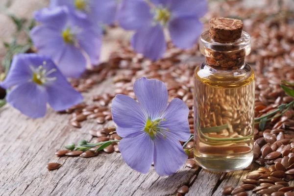 Len olej ve skleněné láhvi closeup, květů a semen — Stock fotografie
