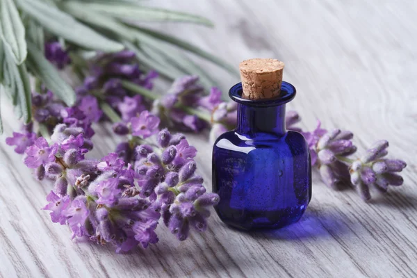 Lavendelöl in einer Glasflasche auf einem Hintergrund Blumen — Stockfoto