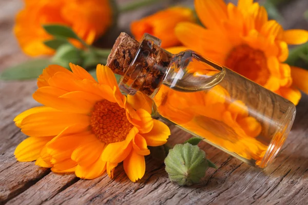 Ringelblumenöl in einer Glasflasche auf einem alten Tisch horizontal — Stockfoto