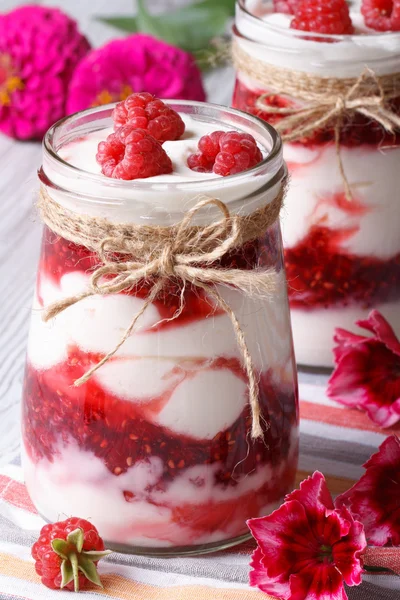 Raspberry dessert in a jar and flower on a table, vertical — Stock Photo, Image