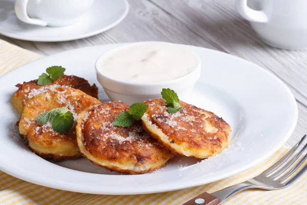 Portion cheese pancakes on a white plate with sour cream — Stock Photo, Image