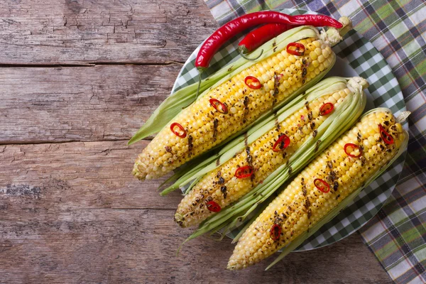 Grilled corn with chili peppers on a wooden top view — Stock Photo, Image