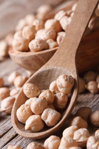 Pile of dried chickpeas in a wooden spoon macro vertical — Stock Photo, Image
