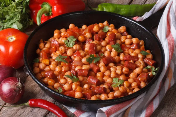 Garbanzos con chorizo en una sartén y los ingredientes —  Fotos de Stock