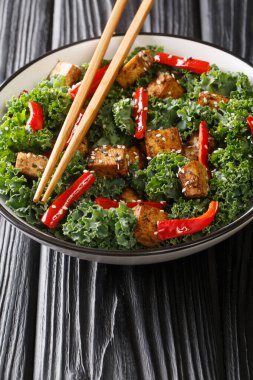 Kızarmış tofu, biber, lahana ve susam tohumlarından yapılmış diyet salatası. Masanın üzerinde yakın plan. Dikey