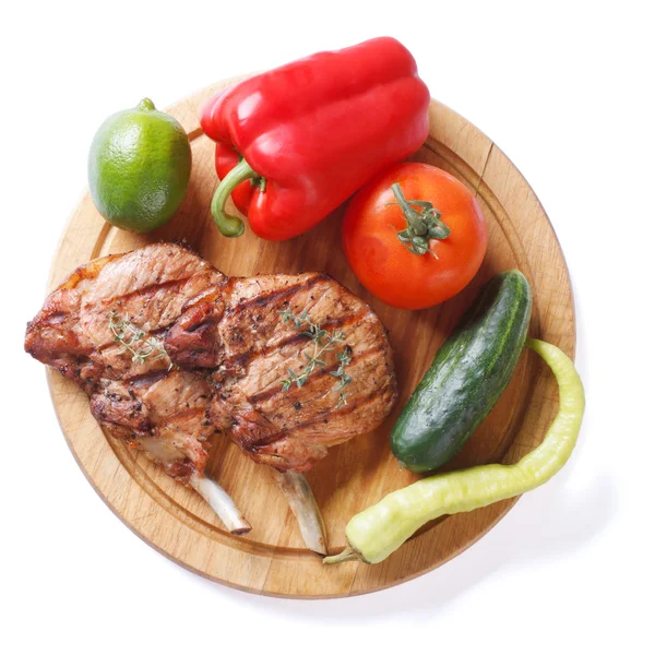 Carne di maiale alla griglia e verdure su un tagliere vista dall'alto isolata — Foto Stock