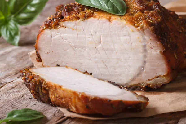 Sliced baked pork fillet and basil close-up on the table — Stock Photo, Image