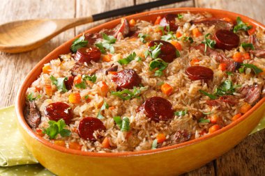 Portekiz ördeği pirinç arroz de pato kırmızı şarap, soğan, havuç ve sucukla pişirilmiş ahşap masadaki fırın kabında yakın çekim. Yatay