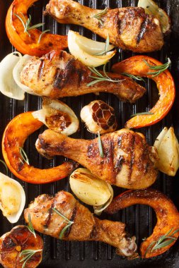 Kızarmış tavuk budu, balkabağı dilimleri, soğan ve yakın plan sarımsaklı siyah ızgara. yukarıdan dikey üst görünüm