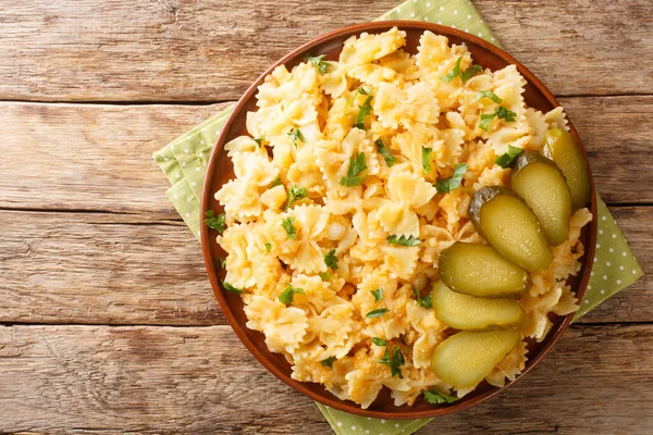 European food Pasta with potatoes and onions served with pickles close-up in a plate on the table. horizontal top view from abov