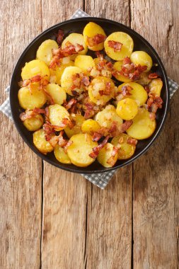 Domuz pastırmalı ve soğanlı kızarmış Alman patatesleri masanın üstünde. yukarıdan dikey üst görünüm