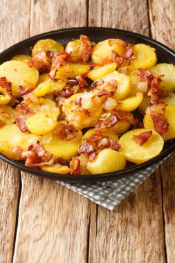 Domuz pastırmalı ve soğanlı kızarmış Alman patatesleri masanın üstünde. dikey