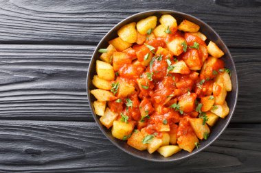 Patatas Bravas tarifi kızarmış patates ve bravas sosu masanın üzerindeki tabağa yakın. Yukarıdan yatay üst görünüm
