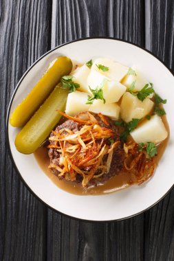 Patates, soğan ve kahverengi sosla servis edilen kıyma kıymalı Danimarka köftelerinden yapılmış hakkebof. Masanın üzerinde. Yukarıdan dikey üst görünüm