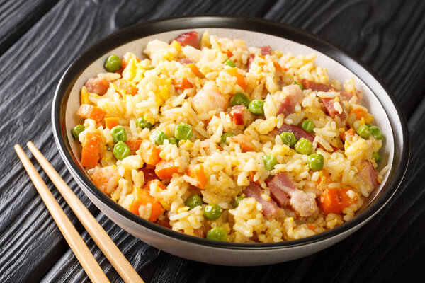 Янчжоу перемешать жареный рис с яйцом и овощами, такими как морковь, горох, а также креветки, мясо близко в тарелке на столе. Фалонта